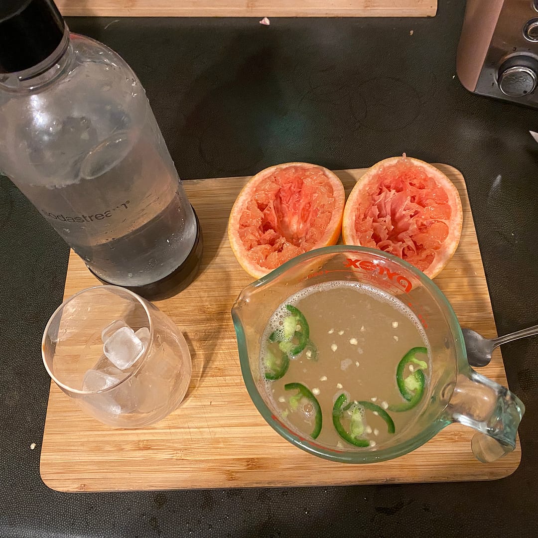 putting the margarita together - sparkling water, marg mix and squeezed grapefuit halves, with ice in glass