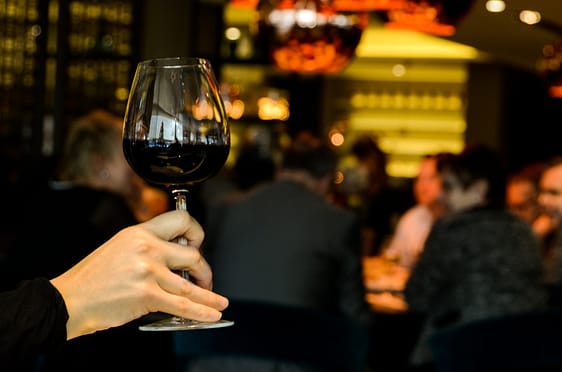 benefits of red wine - woman holding wine in a restaurant